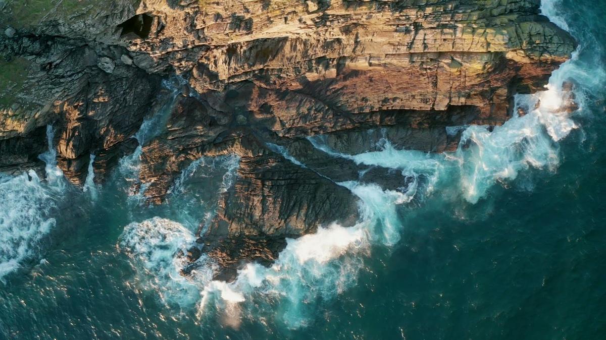 aerial view of waves crashing on the rocks along the coast cornwall UK