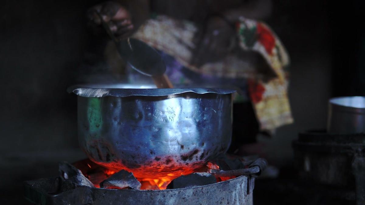 hands of african woman cooking plain food in dark hut at mountain village