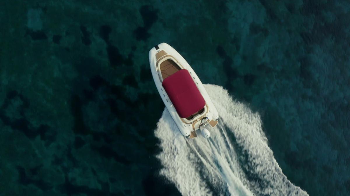 close-up shot over speed boat with a red roof top passing through clear turquoise