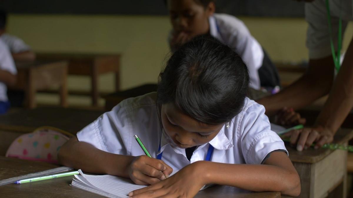 asian girl writing at desk in class